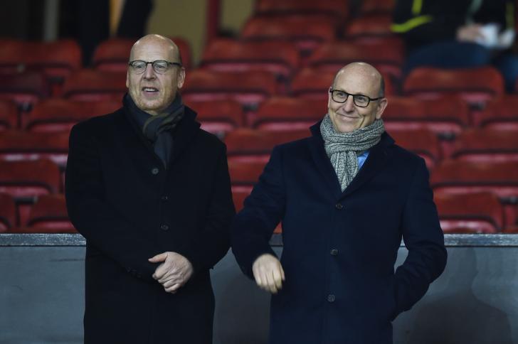 Avram and Joel Glazer stand next to each other wearing scarves and dark coats